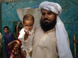 A father along the border between Afghanistan and Pakistan waits to have his son vaccinated against polio. The virus remains endemic in both countries. Photo: Nima Abid/WHO