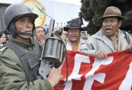 A riot police officer keeps watch over residents shouting slogans outside the military airport in El Alto, where the governor of the northern province of Pando was to arrive after being detained on genocide charges. Photo: Aizar Raldes/AFP/Getty Images