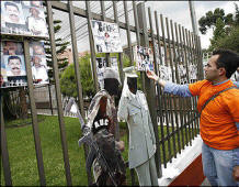 A man places photographs of people murdered or missing, allegedly because of paramilitary groups, on the fence of the Costa Rican Embassy in Bogota, Colombia. Photo: William Fernando Martinez/Associated Press