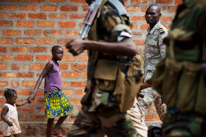 Children walking along the street while two members of a CAR rebel group walk by with guns. Photo: Jacob Zocherman/New York Times&nbsp; with
