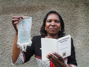 Prof Grace Irimu shows IPS a drip feed bag and a copy of Kenya’s ‘Basic Paediatric Protocols’ as she explains the importance of intravenous treatment in saving the lives of young children affected by acute watery diarrhoea. Credit: Miriam Gathigah/IPS