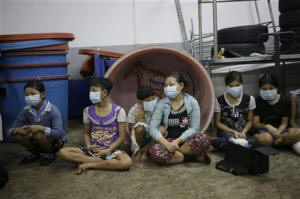 In this Monday, Nov. 9, 2015 photo, children and teenagers sit together to be registered by officials during a raid on a shrimp shed in Samut Sakhon, Thailand.  Photo: AP Photo/Dita Alangkara