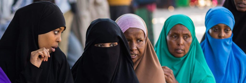 Women in burkas in a line waiting.
