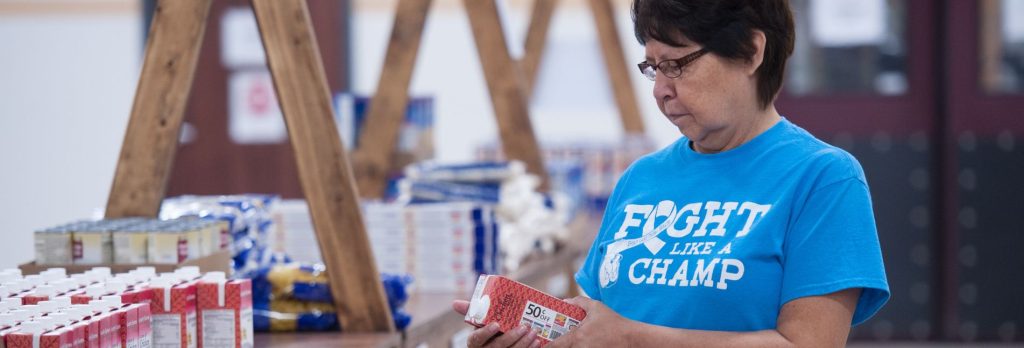 Native American woman looks at canned food label in Spirit Lake Food Distribution Center.
