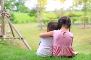 Two children in a yard with backs turned